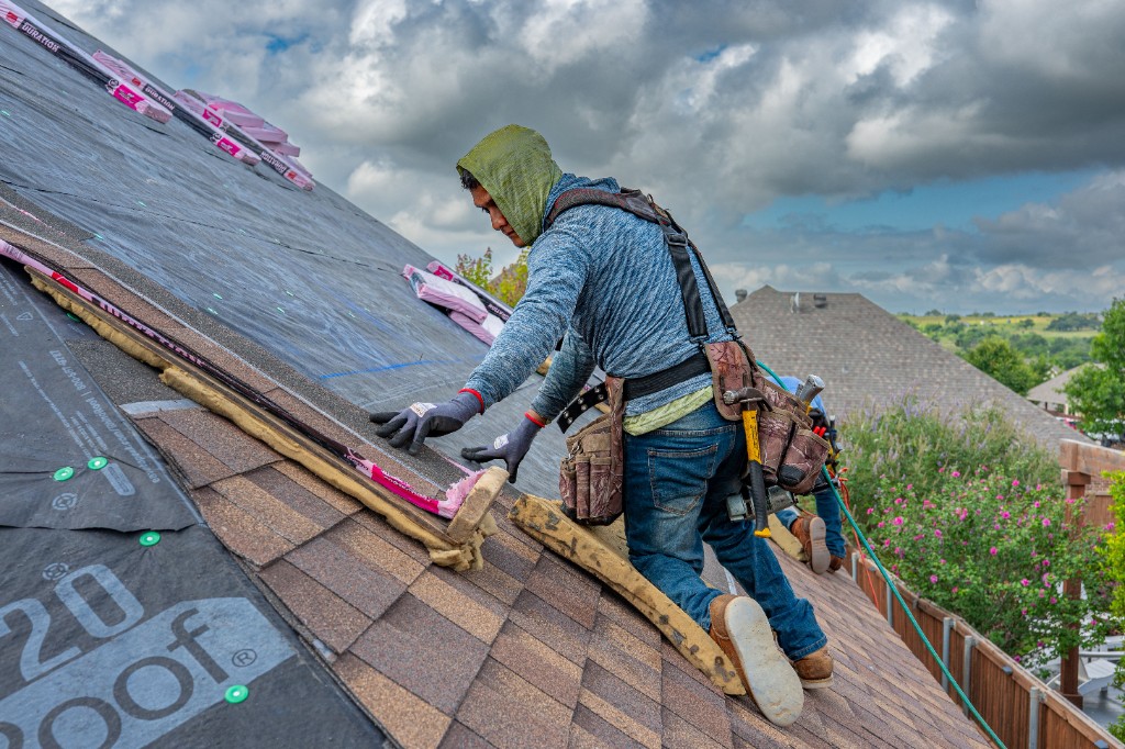 Roofer installing shingles over underlayment on a residential roof