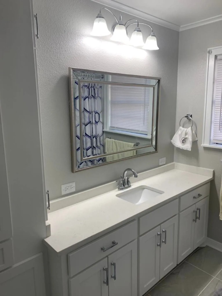 White shaker vanity with quartz countertop and decorative mirror