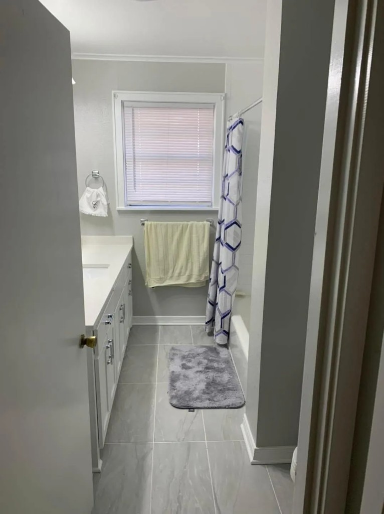 Bright bathroom remodel with long vanity and patterned shower curtain