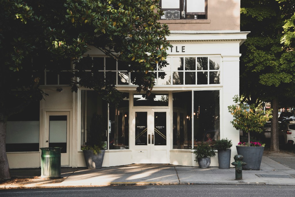 Freshly painted white commercial storefront with large windows and potted plants