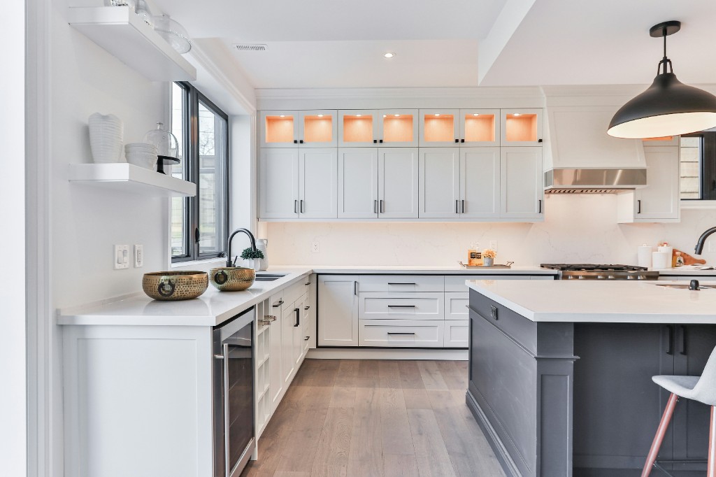 Custom kitchen renovation with white shaker cabinets, a contrasting grey island, and lit glass-front uppers