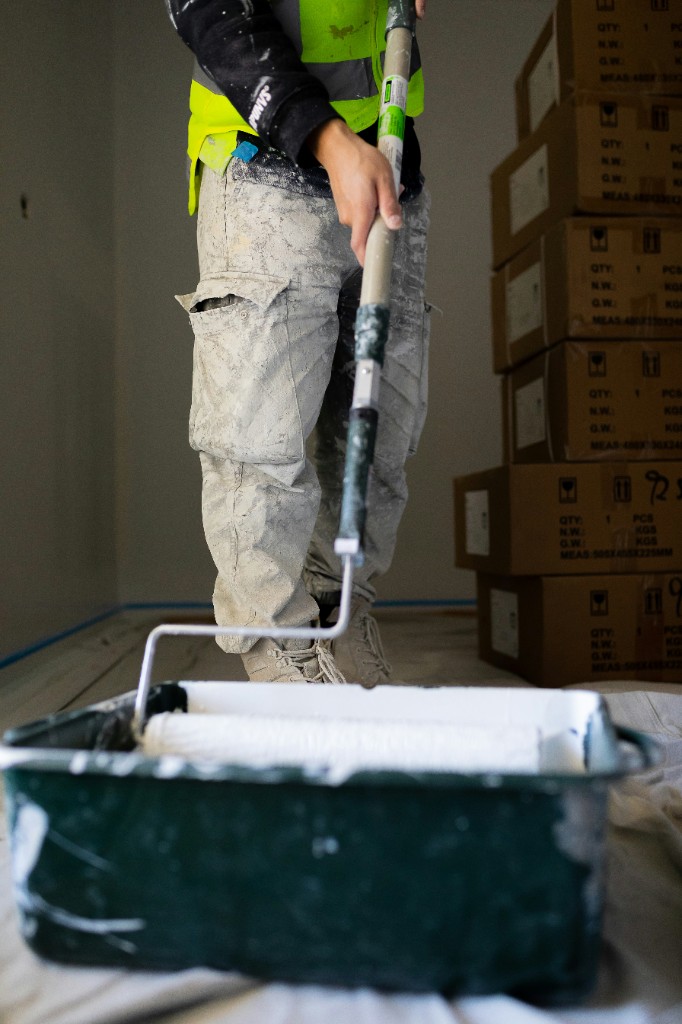 Professional painter rolling fresh paint in an interior room being remodeled